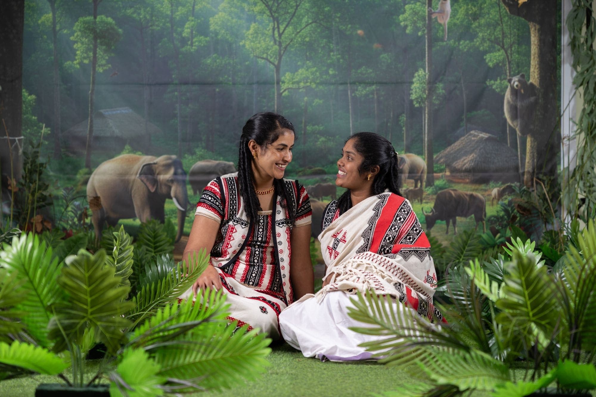 Two guests in traditional Nilgiri dress seated together, laughing
