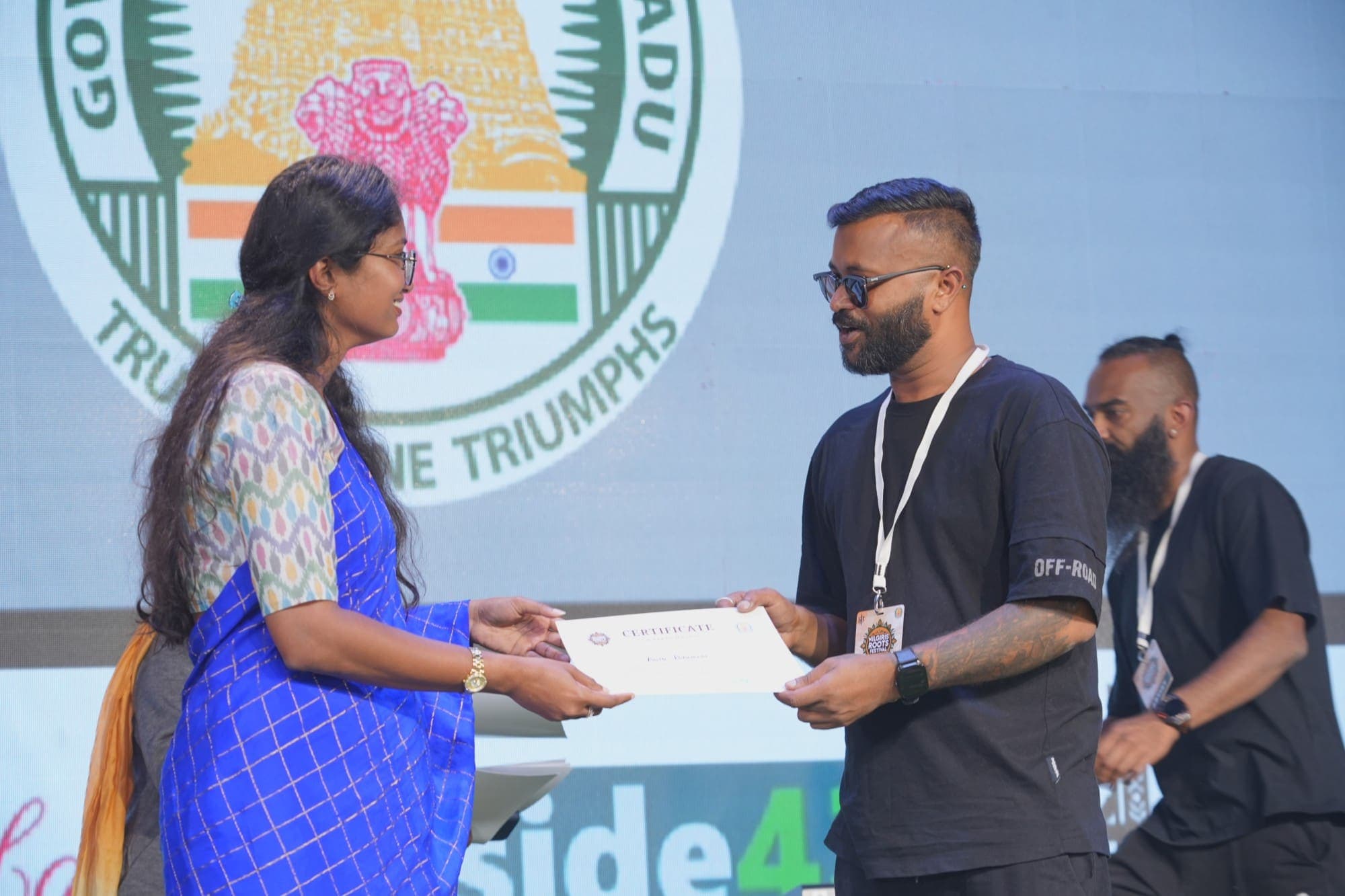 A certificate presented on stage in front of the festival screen